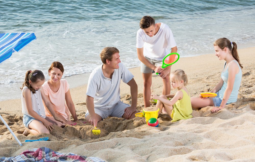 Family playing in sand on the beach.
