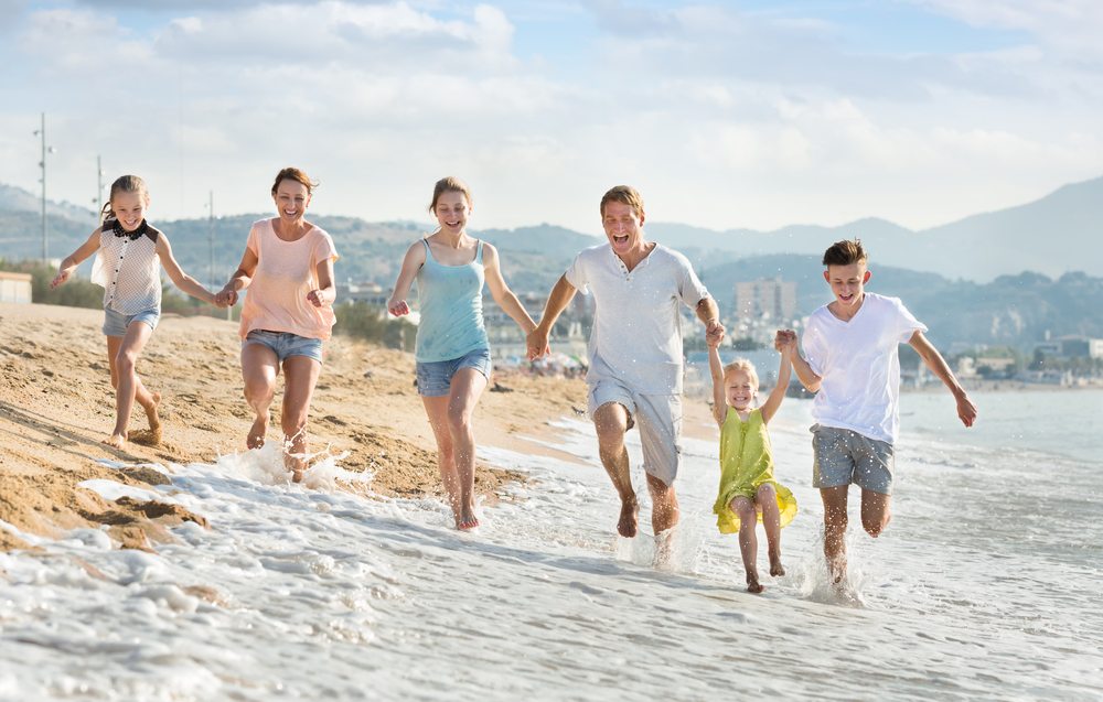 Family running in beach surf.