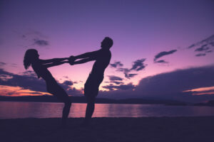 Couple dancing on beach at sunset.