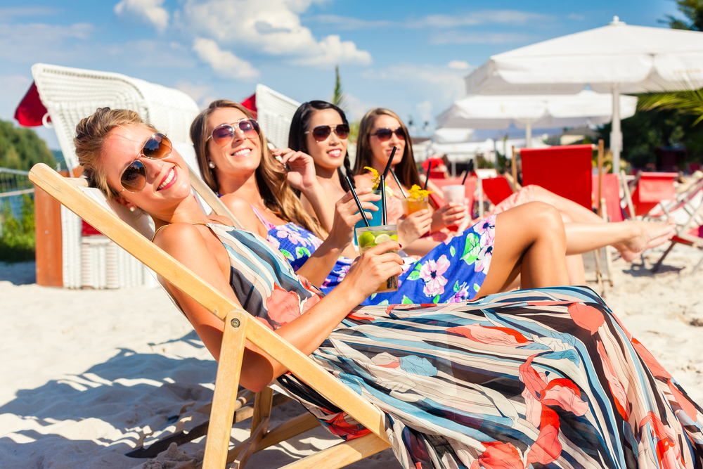 Women in beach chairs with drinks.