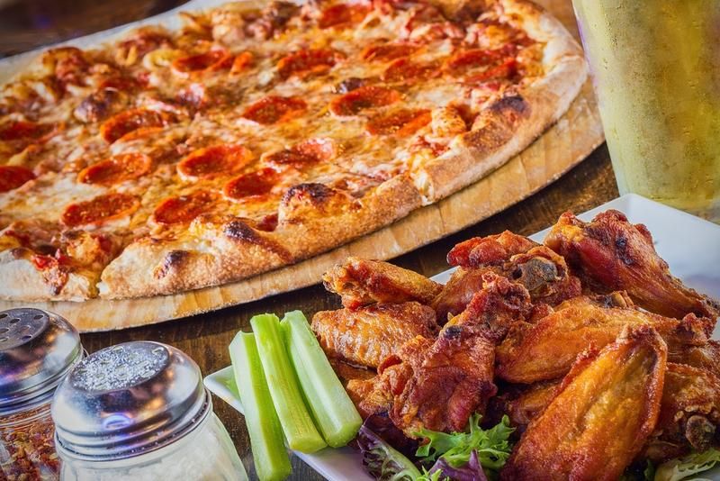 A spread of hot pizza and wings, a convenient meal solution for sports teams and large groups.