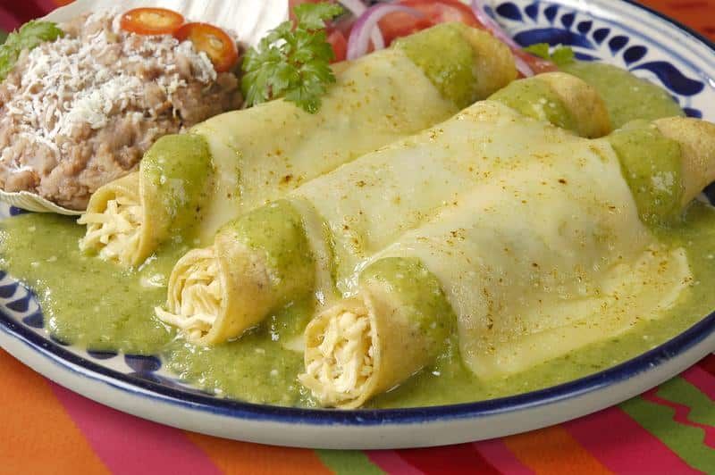 A plate of three fresh enchiladas smothered in green salsa, representing the diverse local restaurant options for resort guests.