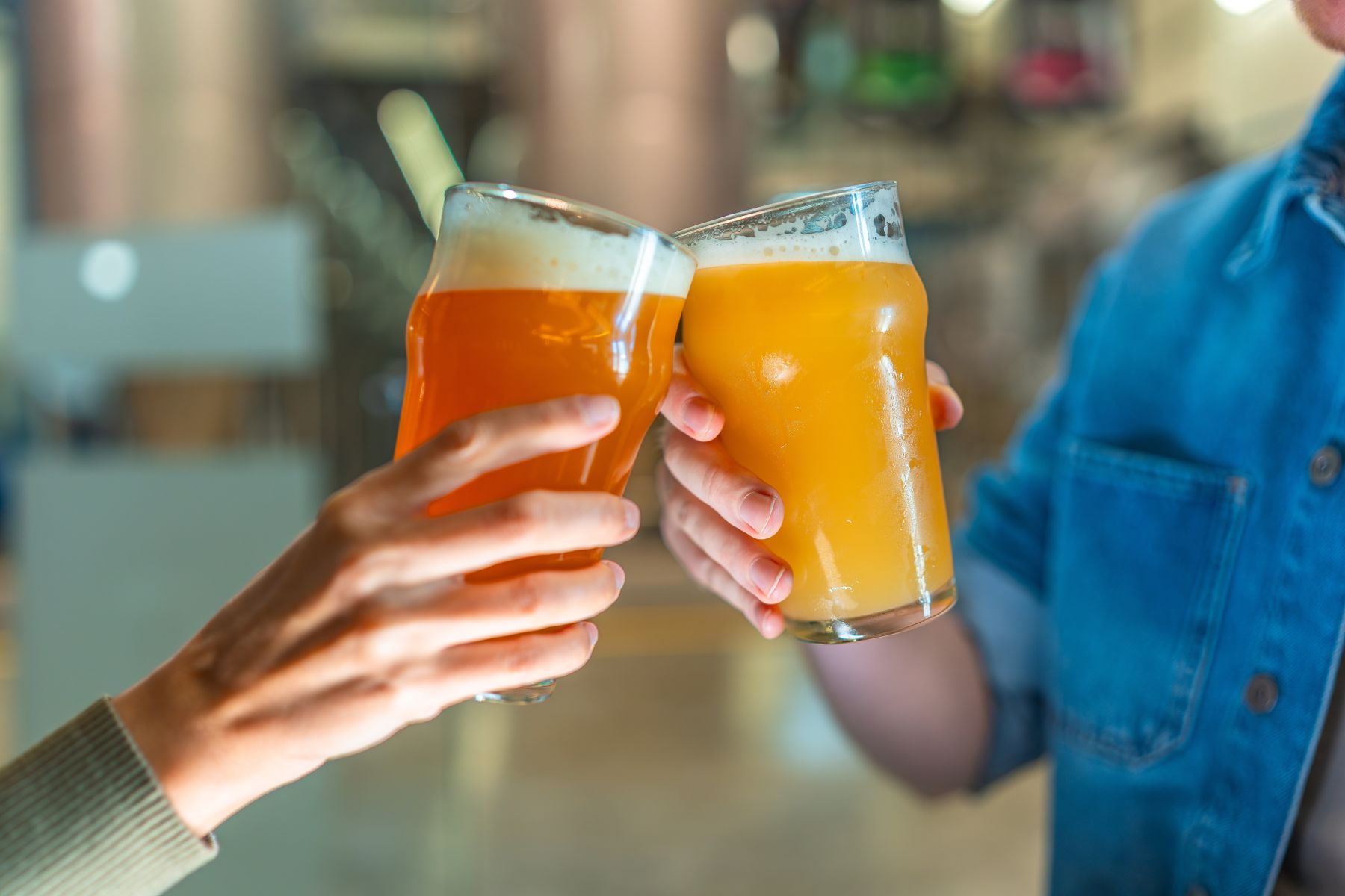 Close-up of two people clinking glasses of hazy craft beer at a local brewery, showcasing the vibrant nightlife and dining scenes near Together Resorts vacation rentals in Myrtle Beach, South Carolina.